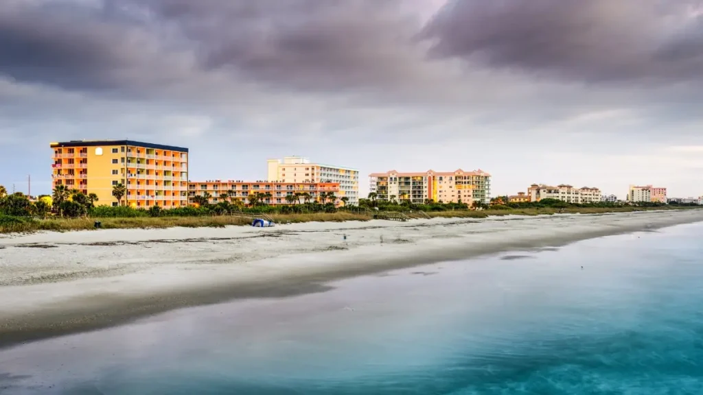 Cocoa Beach Florida beach at sunrise showing surfers, palm trees, and calm Atlantic waves