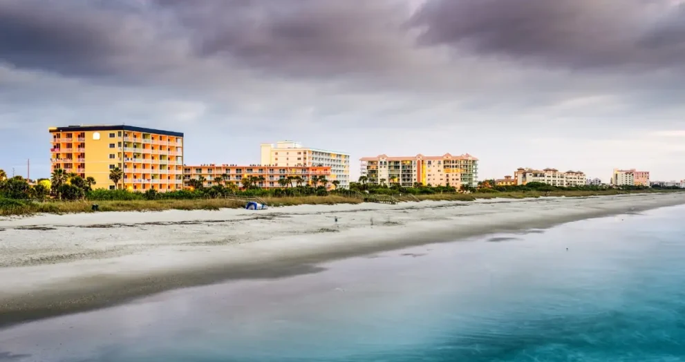 Cocoa Beach Florida beach at sunrise showing surfers, palm trees, and calm Atlantic waves