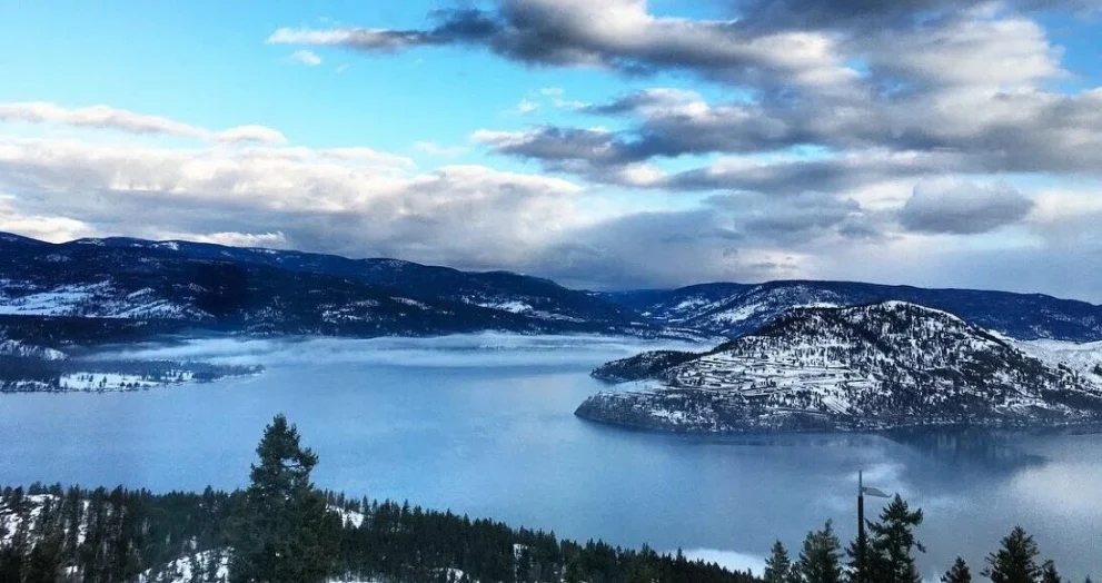 Group enjoying a relaxing holiday celebration with a picnic on scenic hilltop surrounded by mountains and nature