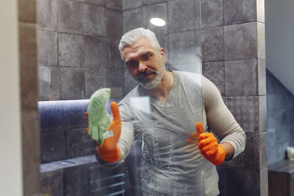 Homeowner using a squeegee on shower glass after showering – the top shower mold prevention habit recommended for US bathrooms in 2026