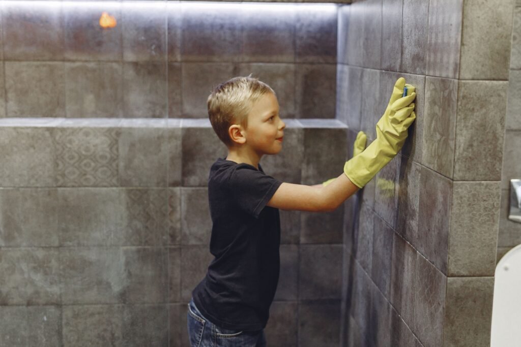 Gloved hand scrubbing black mold from shower grout lines with a brush – proven 2026 method used in American homes to clean shower mold